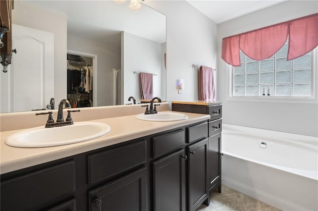 bathroom with a bath, double vanity, and a spacious closet
