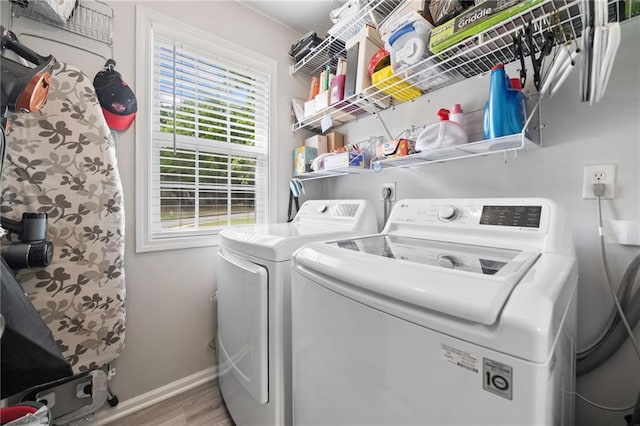clothes washing area featuring washing machine and dryer, baseboards, and wood finished floors