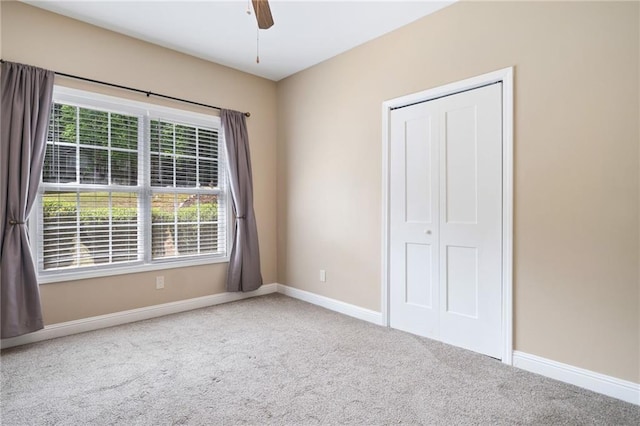 unfurnished bedroom featuring carpet floors, baseboards, a closet, and ceiling fan