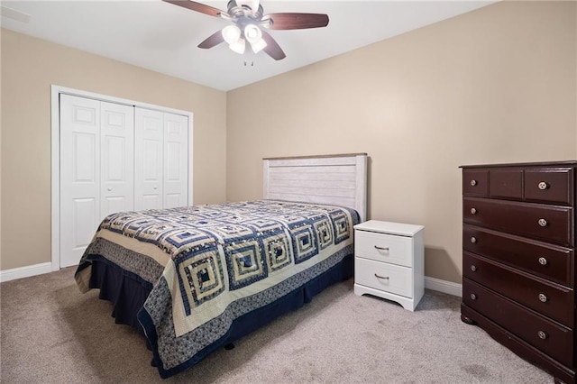 bedroom featuring light colored carpet, a closet, baseboards, and a ceiling fan