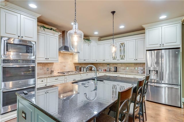 8240 Hurakan Creek Xing, Cumming, GA 30028 - kitchen with stainless steel appliances, a sink, wall chimney exhaust hood, a breakfast bar area, and an island with sink