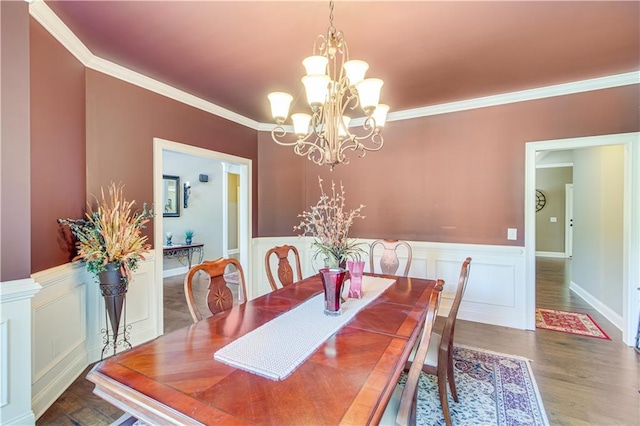8240 Hurakan Creek Xing, Cumming, GA 30028 - dining space featuring crown molding, a wainscoted wall, wood finished floors, a chandelier, and a decorative wall