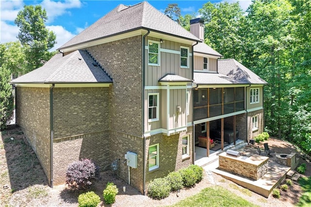 8240 Hurakan Creek Xing, Cumming, GA 30028 - rear view of property with a patio area, an outdoor fire pit, a chimney, a sunroom, and roof with shingles