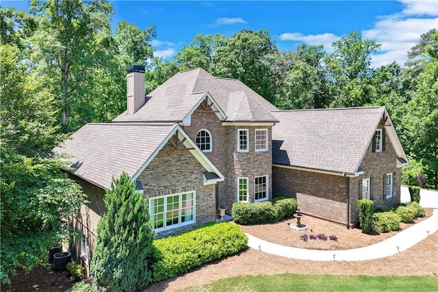 8240 Hurakan Creek Xing, Cumming, GA 30028 - view of front of house with a chimney, stone siding, central air condition unit, and roof with shingles