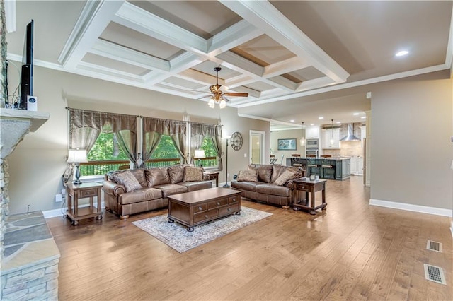 8240 Hurakan Creek Xing, Cumming, GA 30028 - living area with light wood finished floors, a ceiling fan, baseboards, beamed ceiling, and a stone fireplace