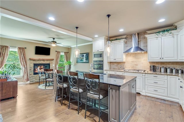 8240 Hurakan Creek Xing, Cumming, GA 30028 - kitchen featuring stainless steel appliances, wall chimney exhaust hood, ornamental molding, a kitchen island, and open floor plan