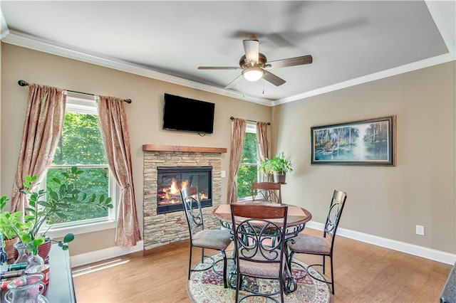 8240 Hurakan Creek Xing, Cumming, GA 30028 - dining area featuring a ceiling fan, baseboards, light wood-style flooring, crown molding, and a stone fireplace