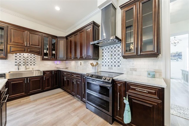 kitchen featuring a sink, wall chimney range hood, dark brown cabinets, light wood-type flooring, and double oven range