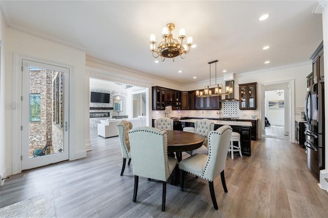 dining area with light wood-type flooring, crown molding, recessed lighting, and an inviting chandelier