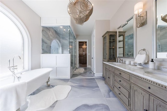 bathroom featuring marble finish floor, double vanity, a stall shower, a sink, and a freestanding tub