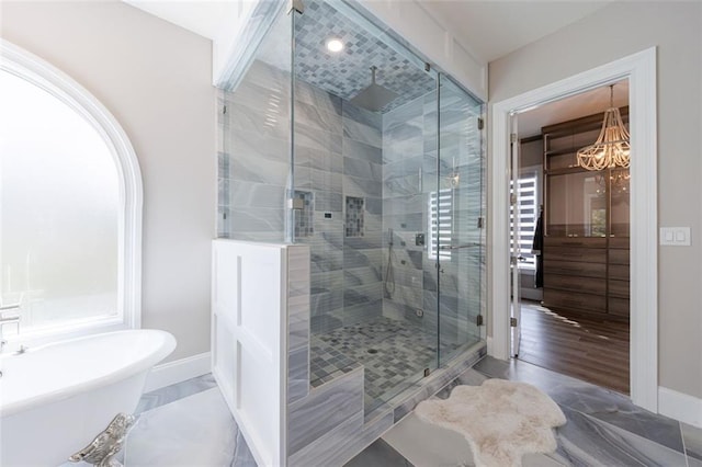 bathroom featuring marble finish floor, a shower stall, baseboards, and a freestanding bath