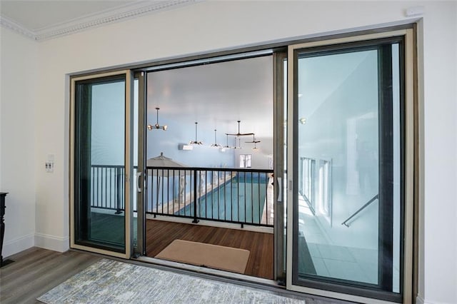 doorway to outside with baseboards, ornamental molding, and wood finished floors