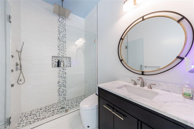 bathroom featuring toilet, tiled shower, and vanity