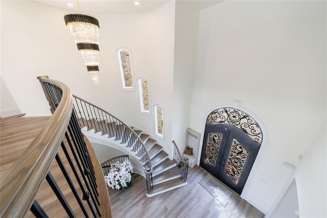 entrance foyer with arched walkways, french doors, stairway, wood finished floors, and a chandelier