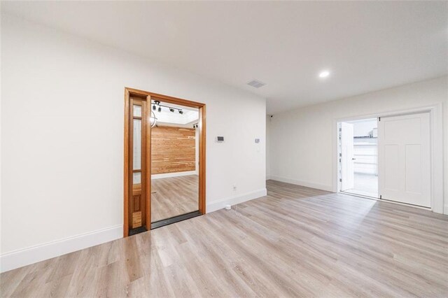 unfurnished room with light wood-type flooring, visible vents, baseboards, and recessed lighting