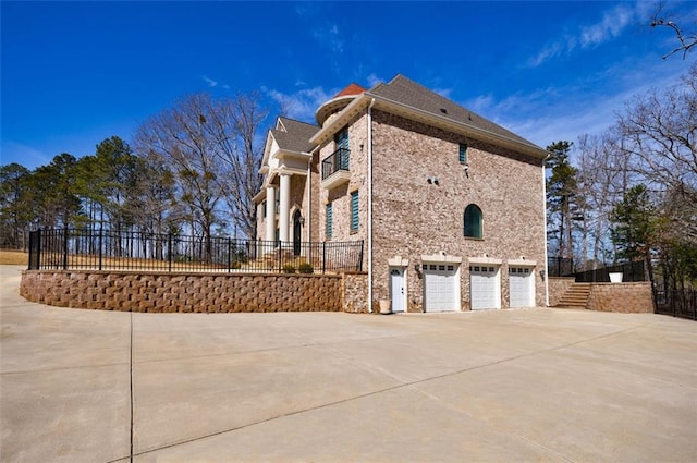 view of home's exterior with an attached garage, brick siding, fence, driveway, and stairway