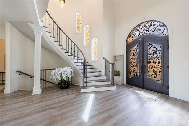 entryway with stairs, french doors, wood finished floors, and a towering ceiling