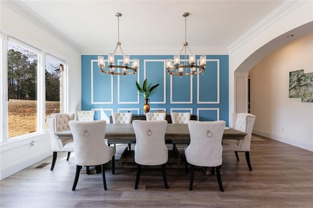 dining area featuring arched walkways, ornamental molding, and wood finished floors