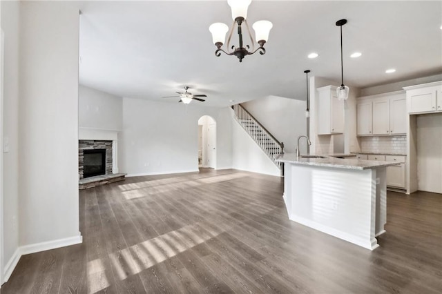 kitchen with backsplash, a stone fireplace, light stone countertops, decorative light fixtures, and white cabinetry