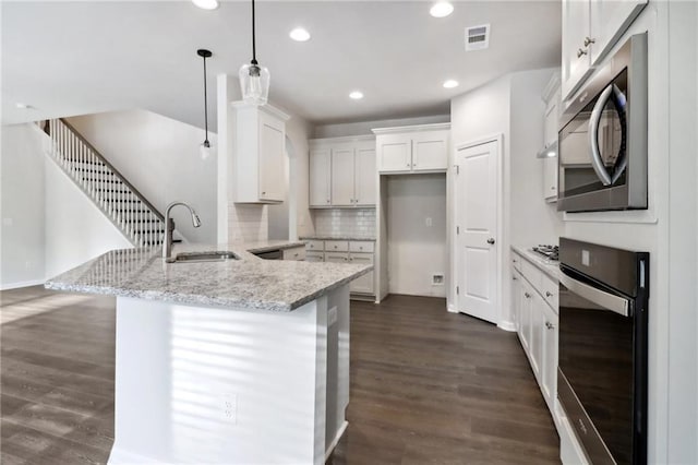 kitchen featuring sink, hanging light fixtures, kitchen peninsula, black oven, and white cabinetry