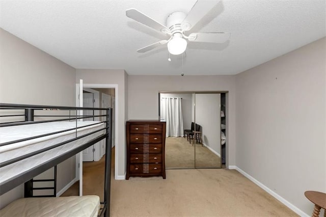 carpeted bedroom featuring ceiling fan, a closet, and a textured ceiling