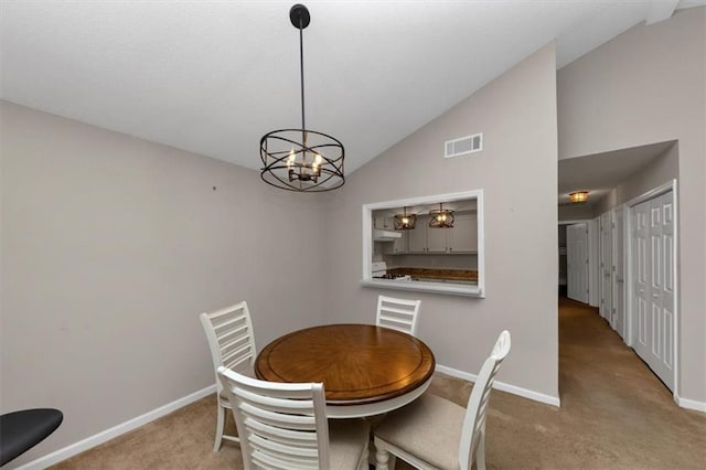 carpeted dining area with an inviting chandelier and vaulted ceiling