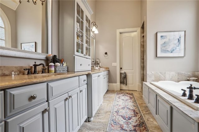 bathroom with an inviting chandelier, vanity, and a bathing tub