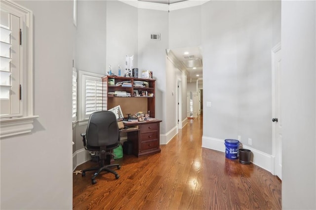 office space featuring a high ceiling, hardwood / wood-style flooring, and crown molding