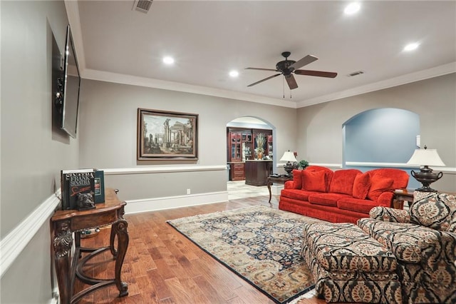 living room with wood-type flooring, crown molding, and ceiling fan