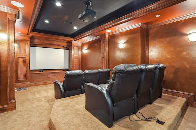 carpeted cinema with ornamental molding and a tray ceiling