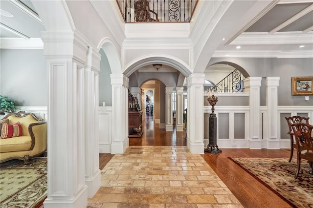 entryway featuring light hardwood / wood-style flooring, a high ceiling, decorative columns, and crown molding