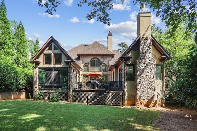 back of property with a lawn, a sunroom, and a wooden deck