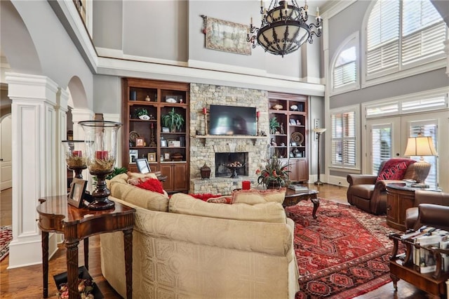 living room featuring a stone fireplace, hardwood / wood-style flooring, a high ceiling, and plenty of natural light