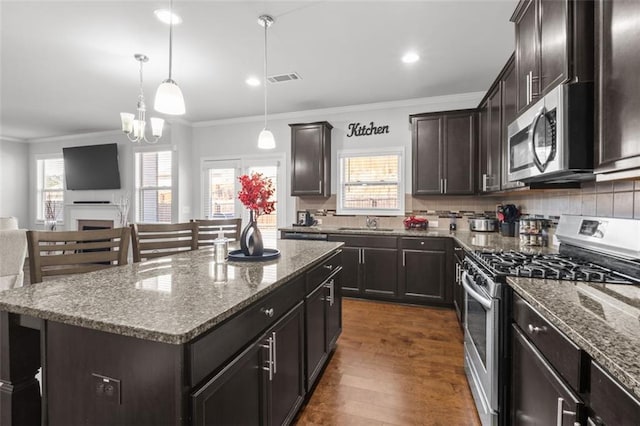 kitchen featuring pendant lighting, dark brown cabinets, stainless steel appliances, and a kitchen island