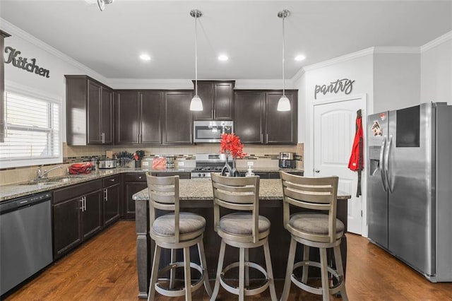 kitchen with stainless steel appliances, dark brown cabinets, a center island, and decorative light fixtures