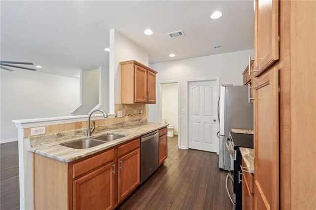 kitchen featuring visible vents, light stone countertops, a sink, dark wood-style floors, and stainless steel appliances