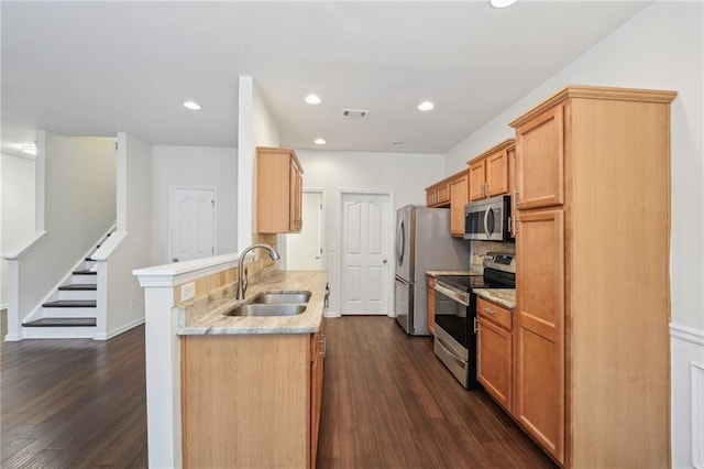 kitchen featuring a sink, dark wood finished floors, appliances with stainless steel finishes, and a peninsula