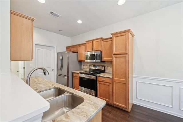 kitchen featuring wainscoting, a sink, stainless steel appliances, tasteful backsplash, and visible vents