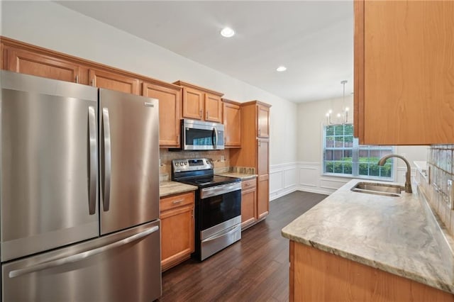 kitchen with an inviting chandelier, wainscoting, dark wood-style floors, a sink, and stainless steel appliances