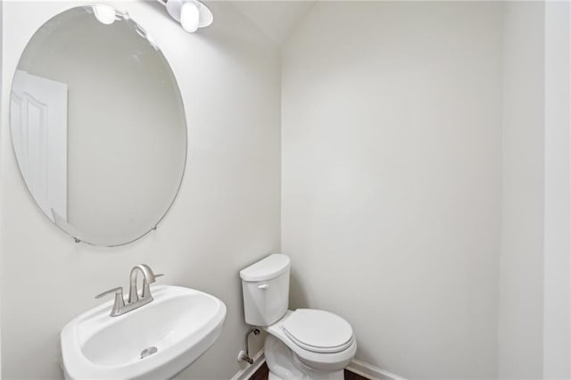bathroom featuring a sink, baseboards, and toilet