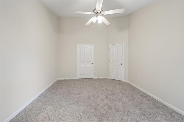 carpeted spare room featuring baseboards, a high ceiling, and a ceiling fan