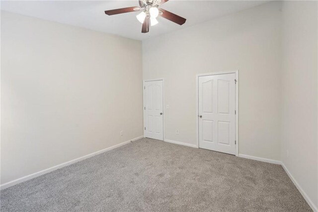 carpeted empty room featuring ceiling fan and baseboards