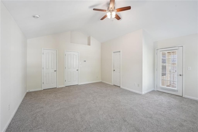 carpeted spare room featuring baseboards, a ceiling fan, and vaulted ceiling