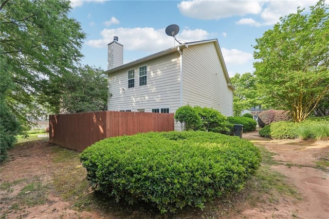 view of property exterior featuring fence and a chimney