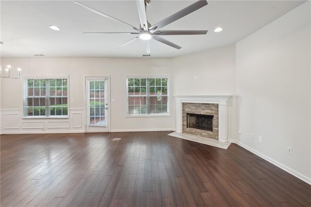 unfurnished living room with recessed lighting, a stone fireplace, wood finished floors, and ceiling fan with notable chandelier