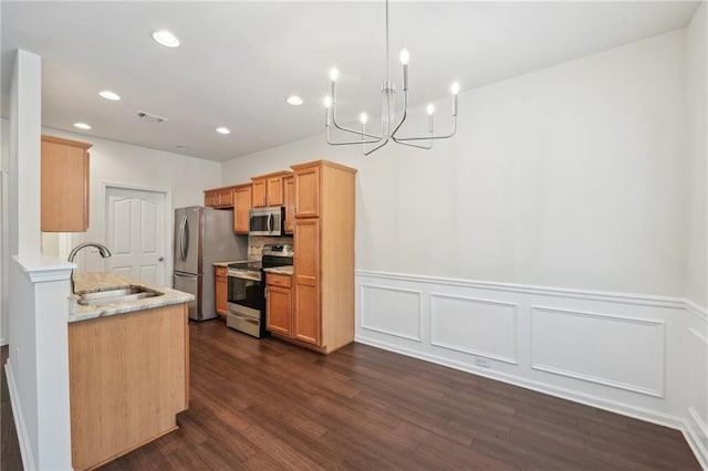 kitchen featuring appliances with stainless steel finishes, a sink, a chandelier, a wainscoted wall, and visible vents