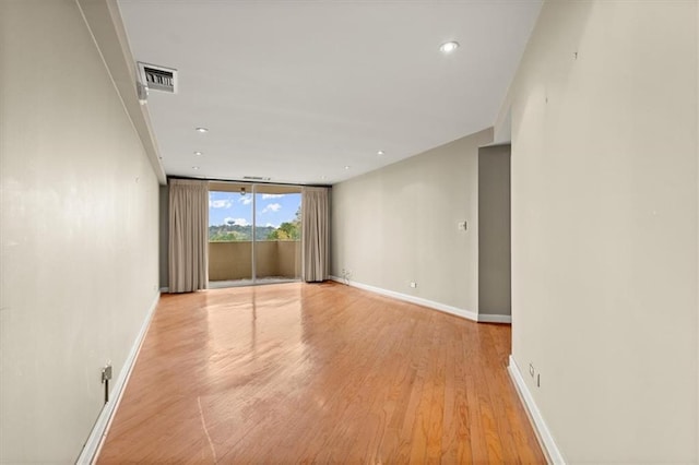 unfurnished room with light wood finished floors, baseboards, expansive windows, and visible vents