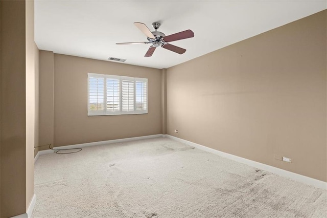 spare room featuring a ceiling fan, light colored carpet, visible vents, and baseboards