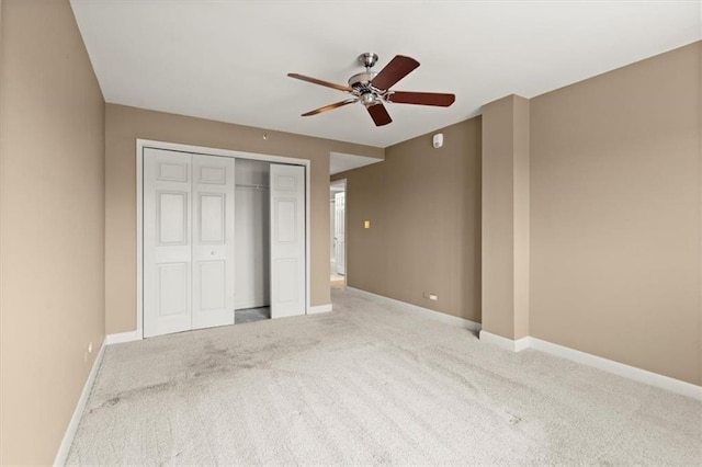 unfurnished bedroom with a ceiling fan, a closet, light carpet, and baseboards