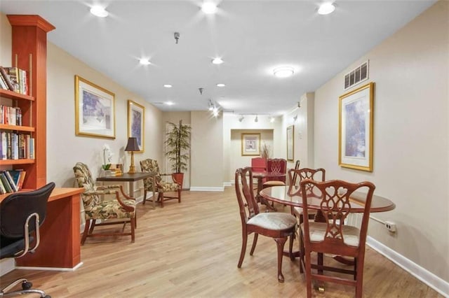 dining space featuring track lighting, baseboards, visible vents, and light wood finished floors